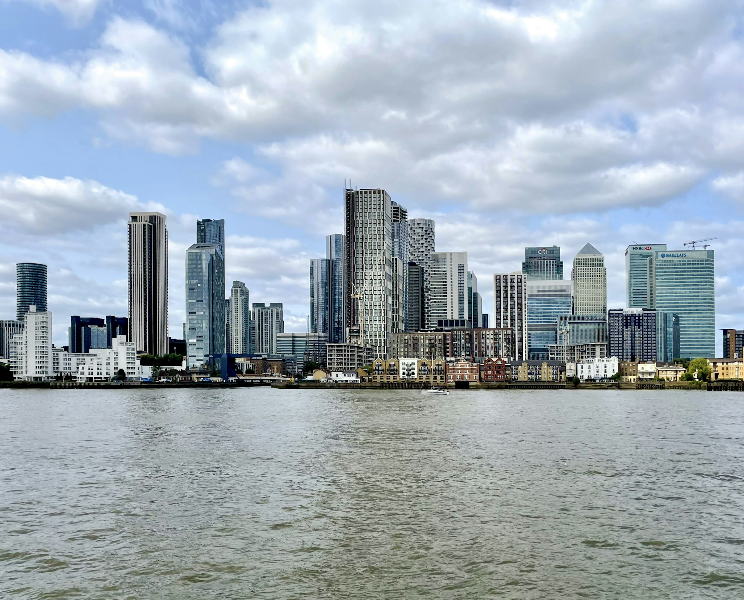 The towers of Canary Wharf seen across a wide expanse of water.