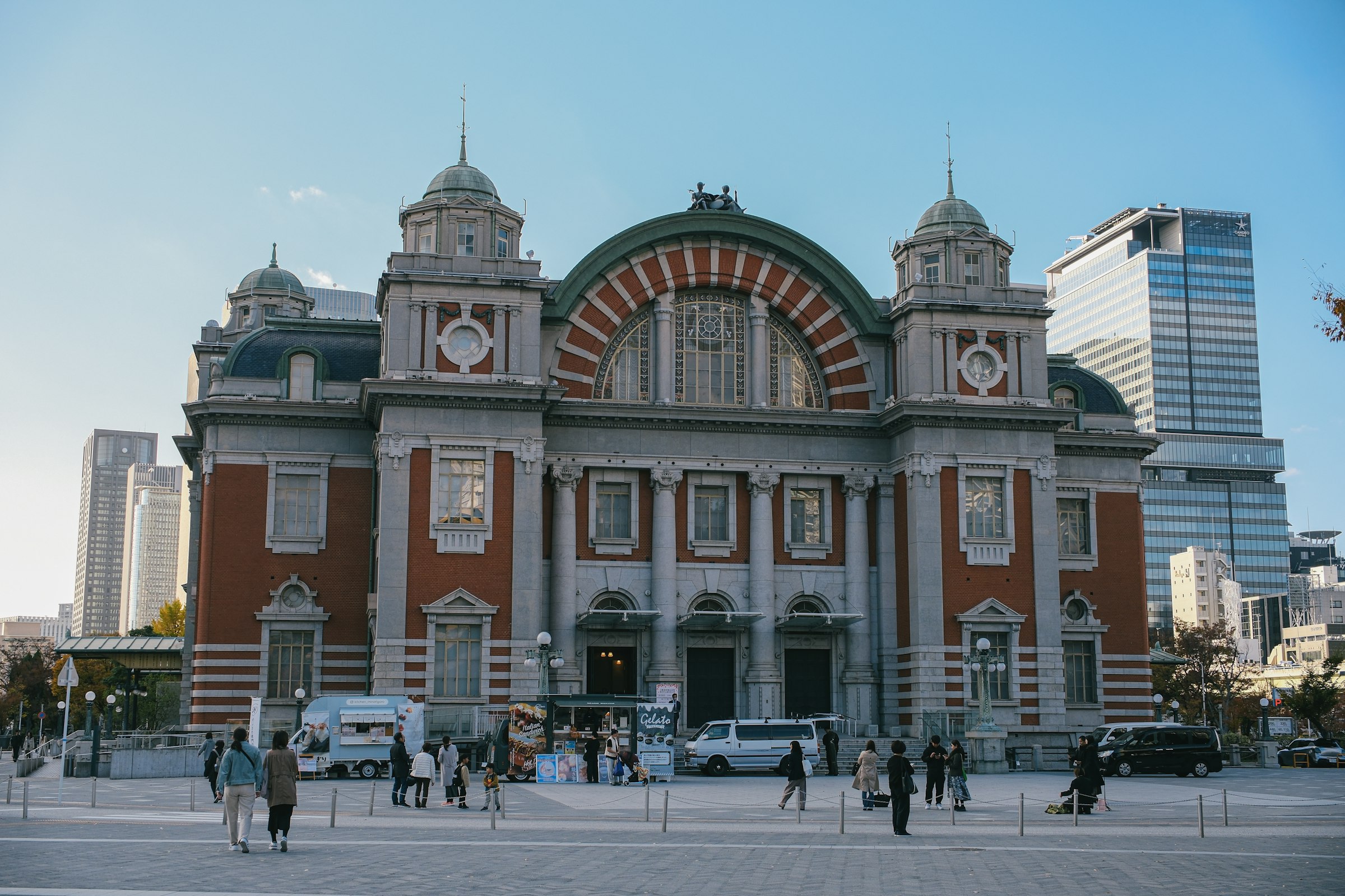 A red-brick hall with a great arched window, with office towers rising behind it.
