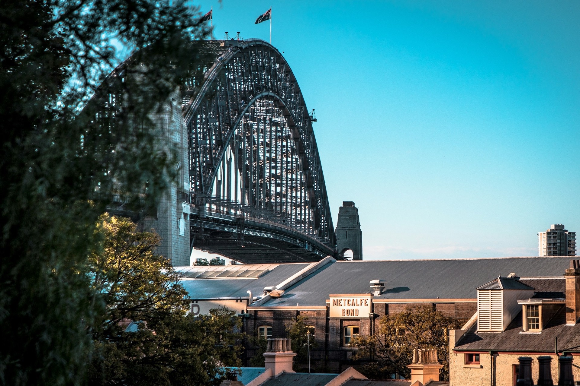 A black-painted terrace house beside the Sydney Harbour Bridge approach at The Rocks, early morning.
